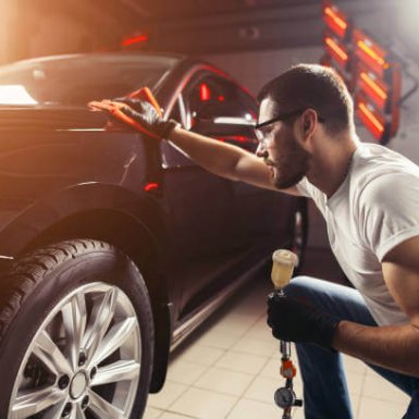 A man cleaning car with microfiber cloth, car detailing or valeting concept. Selective focus.