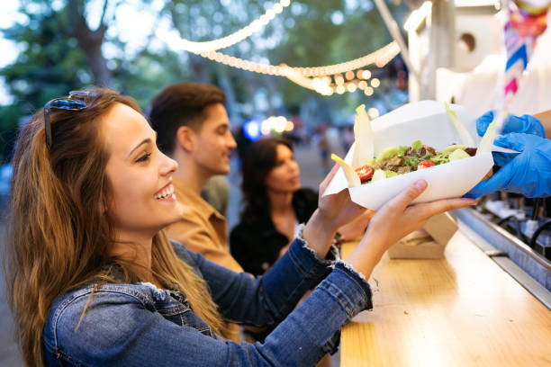 Shot of group of attractive young friends choosing and buying different types of fast food in eat market in the street.