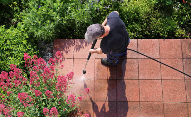 Worker cleaning stone slabs with the high-pressure cleaner, seen from above, with space for text.