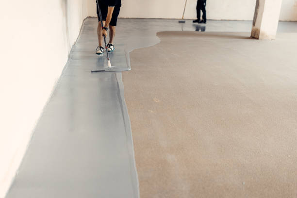 A construction worker apply grey epoxy resin in an industrial hall