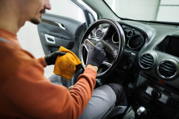 Professional car detailer cleaning car interior with a microfiber towel