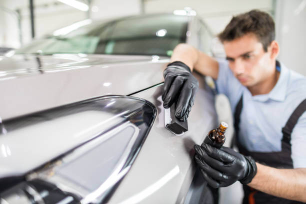 Car detailing - Man applies nano protective coating to the car. Selective focus.