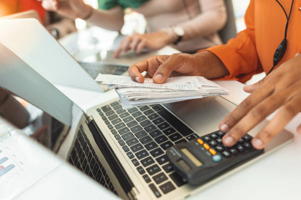 Photo of table full with papers invoices cheque bills, female hands holding receipt calculating company expenses results of incomes, bookkeeper accountant doing paperwork concept