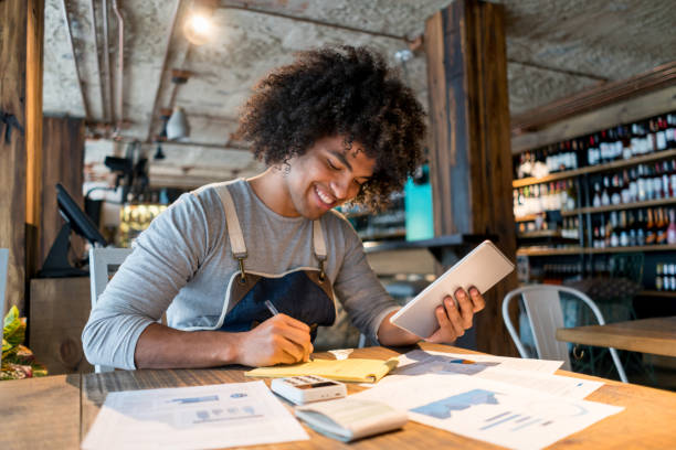 Happy bookkeeper working at a restaurant using a tablet computer and smiling - small business concepts