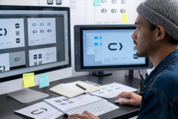 Young Asian graphic designer working in his studio office. Sketching on paper and using computer for work.