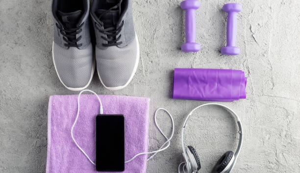 Fitness accessory composition. Sneakers, smartphone and headphones, dumbbell