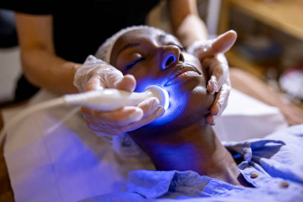 African American woman at the spa getting a rejuvenation treatment on her face using ultrasound and light therapy