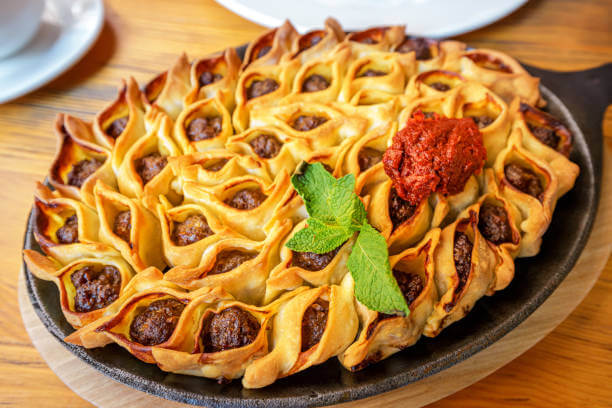 Open manti or dumplings on a frying pan on a table in restaurant. Traditional cuisine of Oriental and Turkic folks