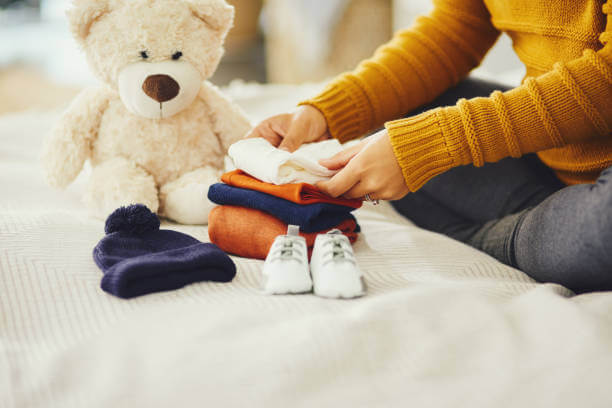 Shot of an unrecognizable pregnant woman sorting out baby clothes in her bedroom at at home