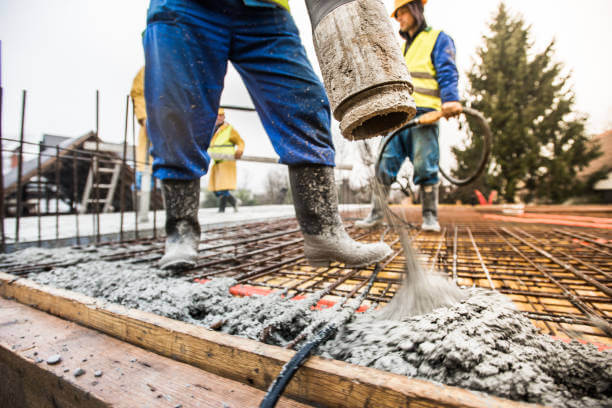 Manual workers pouring cement through pipe on roof.