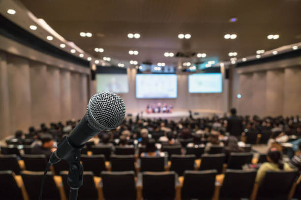 Microphone over the Abstract blurred photo of conference hall or seminar room with attendee background, Business meeting concept