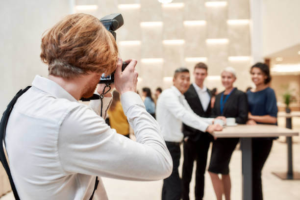 Close up of photographer taking photo of businesspeople during coffee break at business forum. Focus on a photographer. Horizontal shot. Selective focus. Rear view