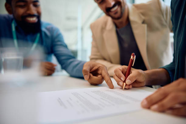 Close up of financial advisor pointing at place of signature on a contract while having a meeting with a couple in the office.