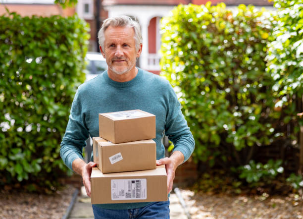 Senior man receiving packages and carrying them to his house - online shopping concepts