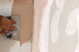 Worker  trowel plastering a wall