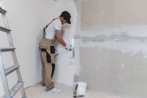 Male painter with a spatula in his hands makes repairs in  home. Room renovation concept.