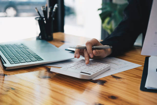 Close up an accountant working about financial with calculator at his office to calculate expenses, Accounting concept.