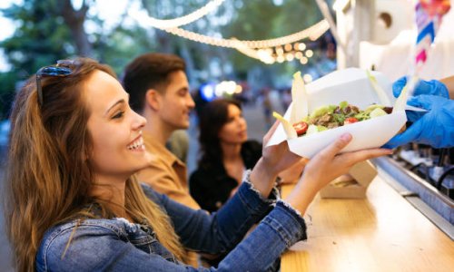 Shot of group of attractive young friends choosing and buying different types of fast food in eat market in the street.