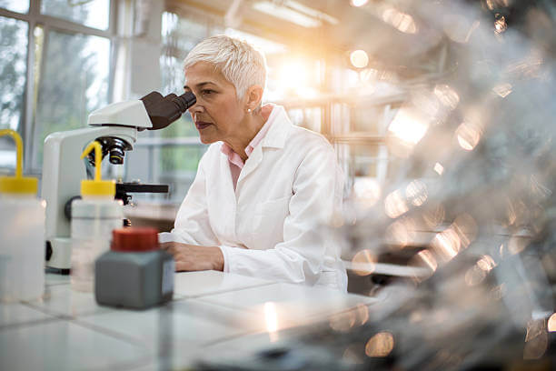 Mature scientist looking through a microscope in a laboratory.