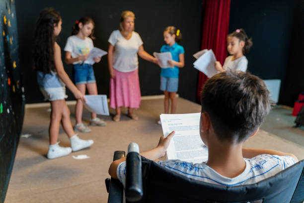 Group of children enjoying drama club rehearsal. They are reading script with their drama teacher.