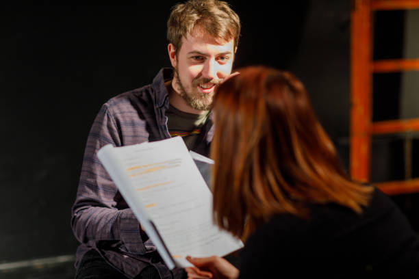 Actors rehearsing with scripts on stage in theater.