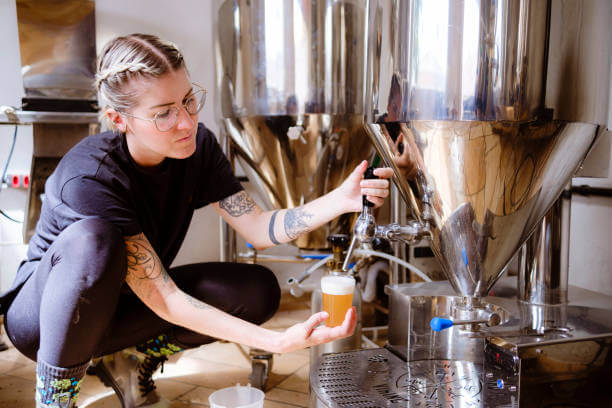 Young woman performing craft beer production step. Small business.