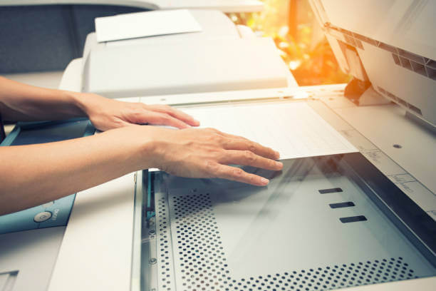 woman hands putting a sheet of paper into a copying device