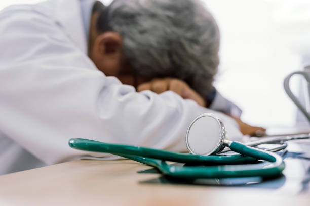 Senior doctor overwork Tired and sleeping on his deck at medical office