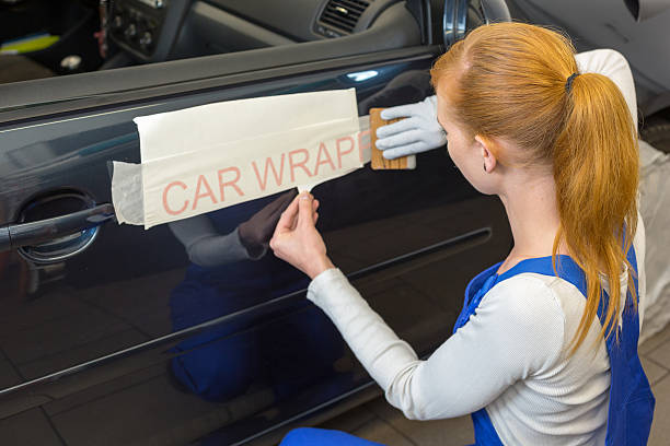 Car wrapping professional puts letters made of vinyl foil or film on vehicle door