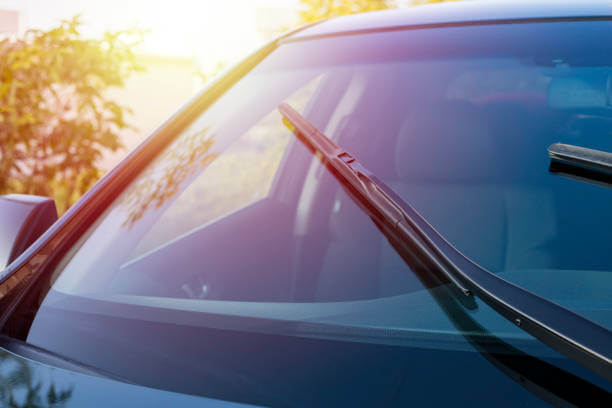 Brushes on the car glass with copy space. The work of windshield wipers - brushes and an evening sunbeam