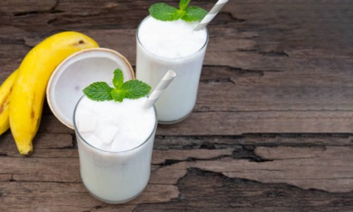 Coconut blend banana milk smoothie drink fresh cocktail shake milkshake vanilla juice fruit beverage food healthy the taste yummy In glass on wooden background from top view.